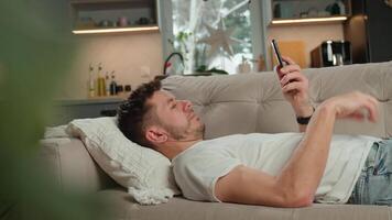 Man relaxing on sofa using smartphone at home video