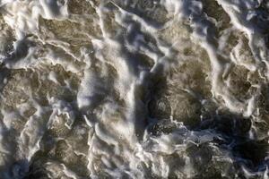 Rough flow of foaming water in the river, close-up, background photo