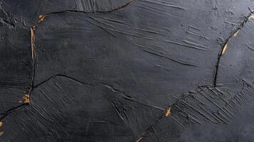 A textured black surface with subtle golden accents, ideal for backgrounds, art projects, or modern design. photo