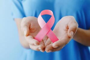 A pair of hands holds a pink ribbon, symbolizing awareness for breast cancer, promoting hope and support for those affected. photo