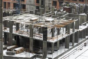 clogged piles in the foreground of a new house under construction in winter against the background of a crane photo