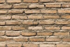 A textured background of a red brick wall with ceramic tiles featuring intricate patterns photo