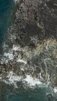 Aerial view of Ocean waves crashing against the rocks of a cliff, vertical footage video