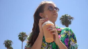 A Young Woman Happily Enjoying a Refreshing Beverage While Relaxing Under Palm Trees video