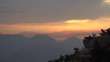 Man on edge of mesmerizing sunset stunning silhouette over the Grand Canyon, with vivid clouds video