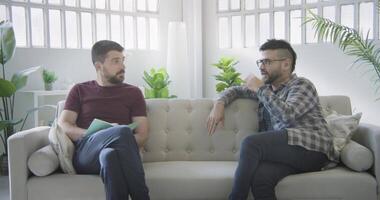 Two men on a couch interview scene talking. video