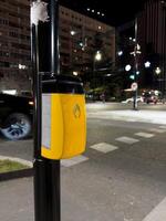 Vertical photography of device with button for switching traffic lights for pedestrians. Facilities in city for pedestrians when crossing road. Pole with button for pedestrian crossing at night photo