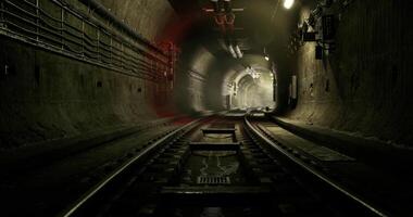 Dark tunnel with train tracks illuminated by distant light video