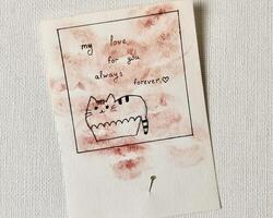 A handmade Valentine's Day card with a cute doodle of a cat and a loving message pinned to a white wall. Unique and heartwarming, perfect for themes of love, creativity, and DIY crafts. photo