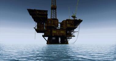 Rusty oil rig emerges from calm waters at twilight near an open sea video