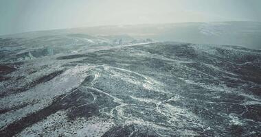 Snow covered landscape with distant hills under a cloudy sky in winter video