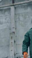 Human in protective costume and mask in infected place. Survivor man in a mask and a chemical protection suit showing on the camera with a finger. Vertical video