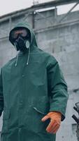 Man wearing hazmat suit in polluted zone. Worker in protective suit, mask and gloves in abandoned place with biological attack threat. Vertical video