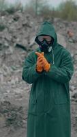 Portrait of a human in hazmat suit and respirator. Man in a protective suit and gas mask on the background of destroyed place. Vertical video
