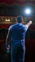 Middle age male entertainer, presenter or actor on stage. Public speaker gives performance in front of empty auditorium. Man in theater. Vertical video