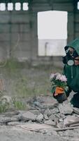 Woman in safety uniform in abandoned place. Scientist in protective suit and respirator with tendy flowers in ruined building. Environment in danger. Vertical video