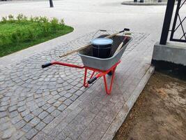 An iron wheelbarrow with red handles for transporting building materials in the garden and backyard. photo