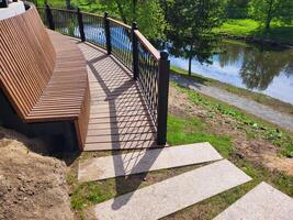 Railings and a brown bench with a high back made of narrow slats photo