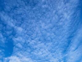 There are patches of small white clouds in the blue sky. A bright sunny summer day photo