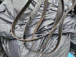 Three old timing belts are lying on a pile of garbage bags. photo