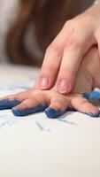 Imprint of children's hands made with paint. Child making hand prints on paper Vertical video