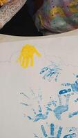 Child making hand print on paper. Colorful designs with hands. Little painter. Vertical video