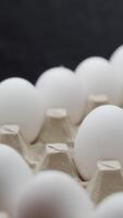 Eggs are getting put into carton tray. Crates of fresh eggs at a poultry farm. Vertical video