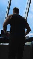 Fitness man athlete training using treadmill. Sportsman doing intense cardio workout challenge enjoying running practice in gym. Slow motion. Back view. Vertical video