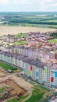 Modern residential complex in the countryside. Colorful high-rise buildings on a construction site. New microdistrict is building. Aerial view. Vertical video