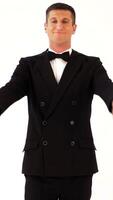 handsome man in a suit with bow-tie is posing in front of a mirror at the exit of the room. Parody of the gentleman on the white background Vertical video