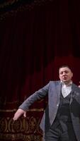 Comedian rehearsing on scene. Happy male actor performing in the theater dancing and singing on stage. Orbital shot. Vertical video