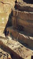 worker is drills stones with using pneumatic tool in the sand quarry. Camera motion up. Aerial view Vertical video