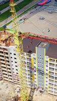 Construction of a multi-storey apartment building. Building of a multi-quarter houses in the city. Tower crane on a construction site. Aerial view. Vertical video