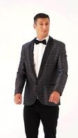 a man in a checkered suit with a bow-tie is parodying manners of macho on a white background in the studio. Vertical video