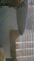 a professional machine is cutting a large stone in the building of a stone processing plant. Stone processing technology using water Vertical video
