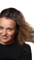 pretty woman with long hair is turning around and posing for the camera in the studio on a white background. Close-up Vertical video