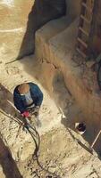 a man is drilling stones with using power tool in a sand quarry. Camera motion up Vertical video
