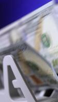 Currency counting machine counts 100 dollar bills. Cash bill counter money machine. Automatic mechanism for bank financial operations. Finance concept. Close-up. Vertical video