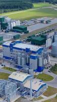 Contemporary factory on green nature background. Grain elevators for drying and storing crop. New industry on field. Aerial view. Vertical video