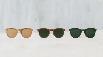 Three pairs of stylish wooden sunglasses arranged artfully on a sandy surface against a soft, blurred background photo
