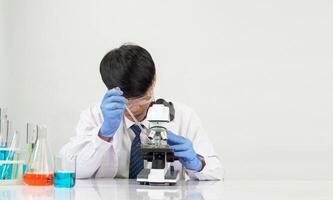 Asian man student scientist reagent mixing laboratory In a science research laboratory with test tubes of various sizes and microscopes. on the table in laboratory chemistry lab white background photo