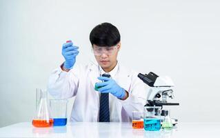 Asian student scientist in reagent mixing laboratory In a science research laboratory with test tubes of various sizes and microscopes. on the table in laboratory chemistry lab white background photo