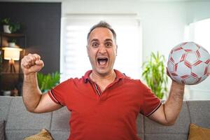 Excited middle aged man watching soccer game at home photo