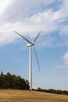 One white wind generator produces alternative energy by wind on the fields in Europe in Spain. Vertical photo