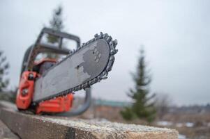 An old working chainsaw is lying on a sawn board fifty millimeters. Photos on the street in the yard for ideas for building from wood and planks. High quality photo
