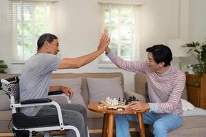 Father and son celebrating a chess move with a high five in a cozy living room, emphasizing family joy and connection. photo
