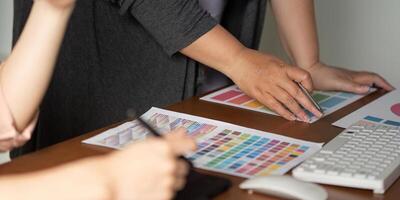 Diverse graphic design team analyzing color samples and prototypes at a table. photo