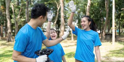 Excited family volunteers celebrating their garbage collection efforts in a park, highlighting teamwork and environmental enthusiasm. photo