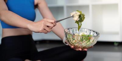 Woman holding a bowl of healthy salad, preparing to take a bite with a fork. photo