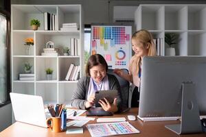 Diverse graphic design team sharing ideas and laughing while using a tablet. photo